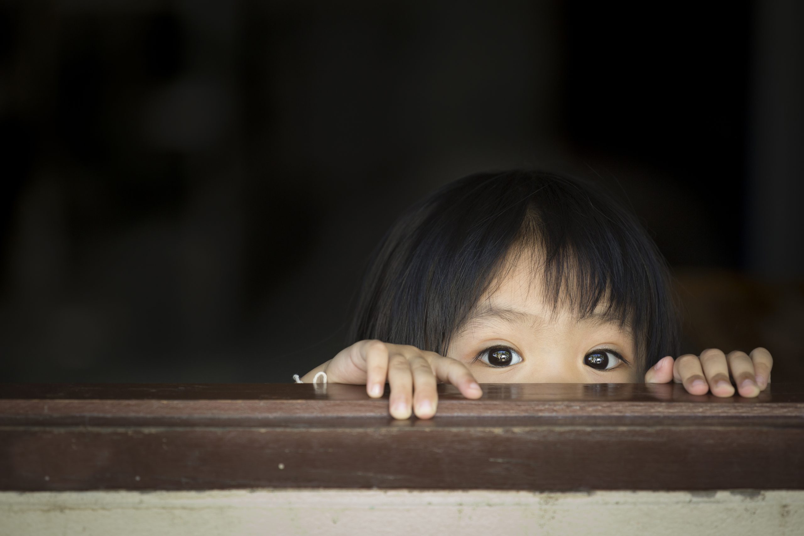 young girl peeking over a wall